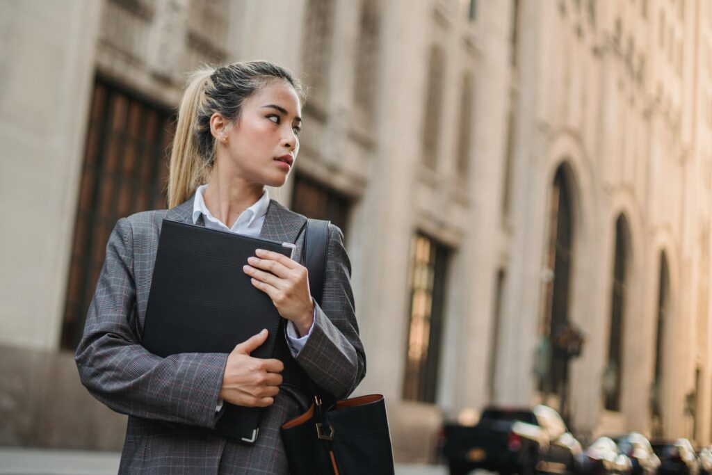 A professional woman in a suit holds a folder on a city street, exuding confidence.